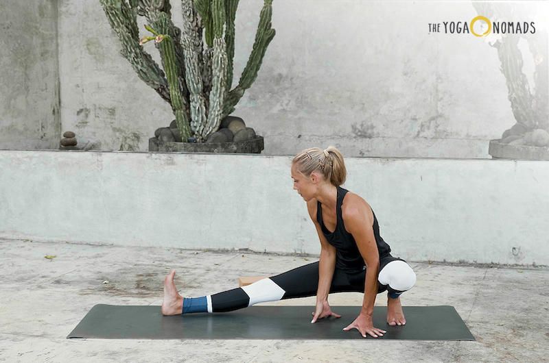 The image shows an individual performing a yoga pose on a yoga mat. The person’s face is obscured with a brown rectangle for privacy. In the background, there is a large cactus plant and a plain wall, indicating the setting may be outdoors or in a spacious indoor area with natural element.