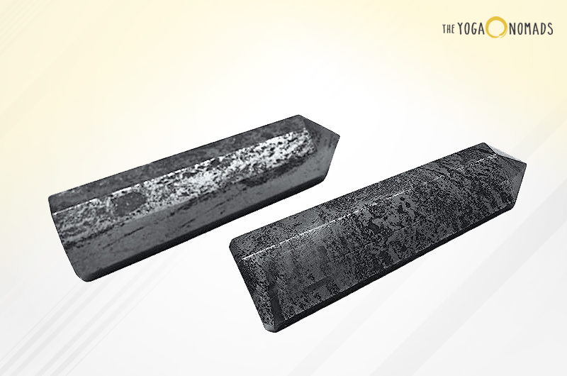 Two elongated, rectangular hematite stones with a metallic sheen and textured surfaces. They are placed against a light background that fades from white to yellow.