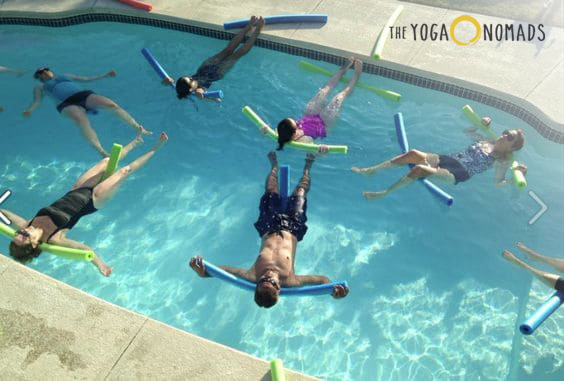 A group of individuals floating in a swimming pool using flotation devices.